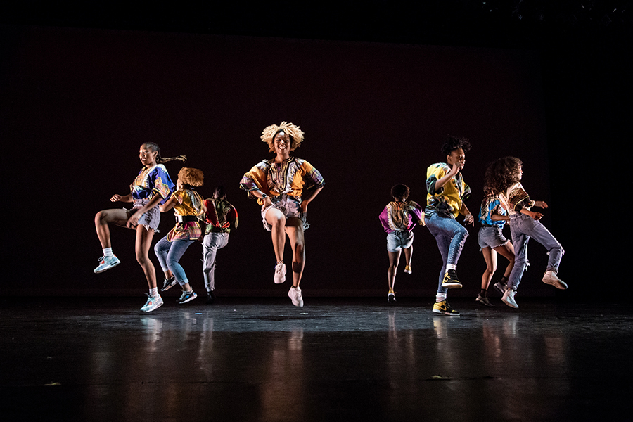 Group of dancers in motion on a black stage