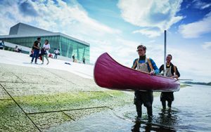 people standing in ankle-deep water while holding up a canoe