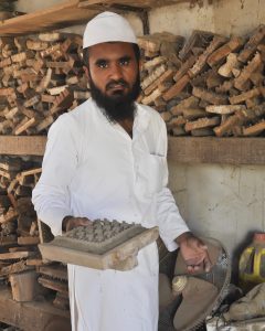 artist standing before shelves of materials