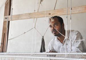 artist behind a carpet loom