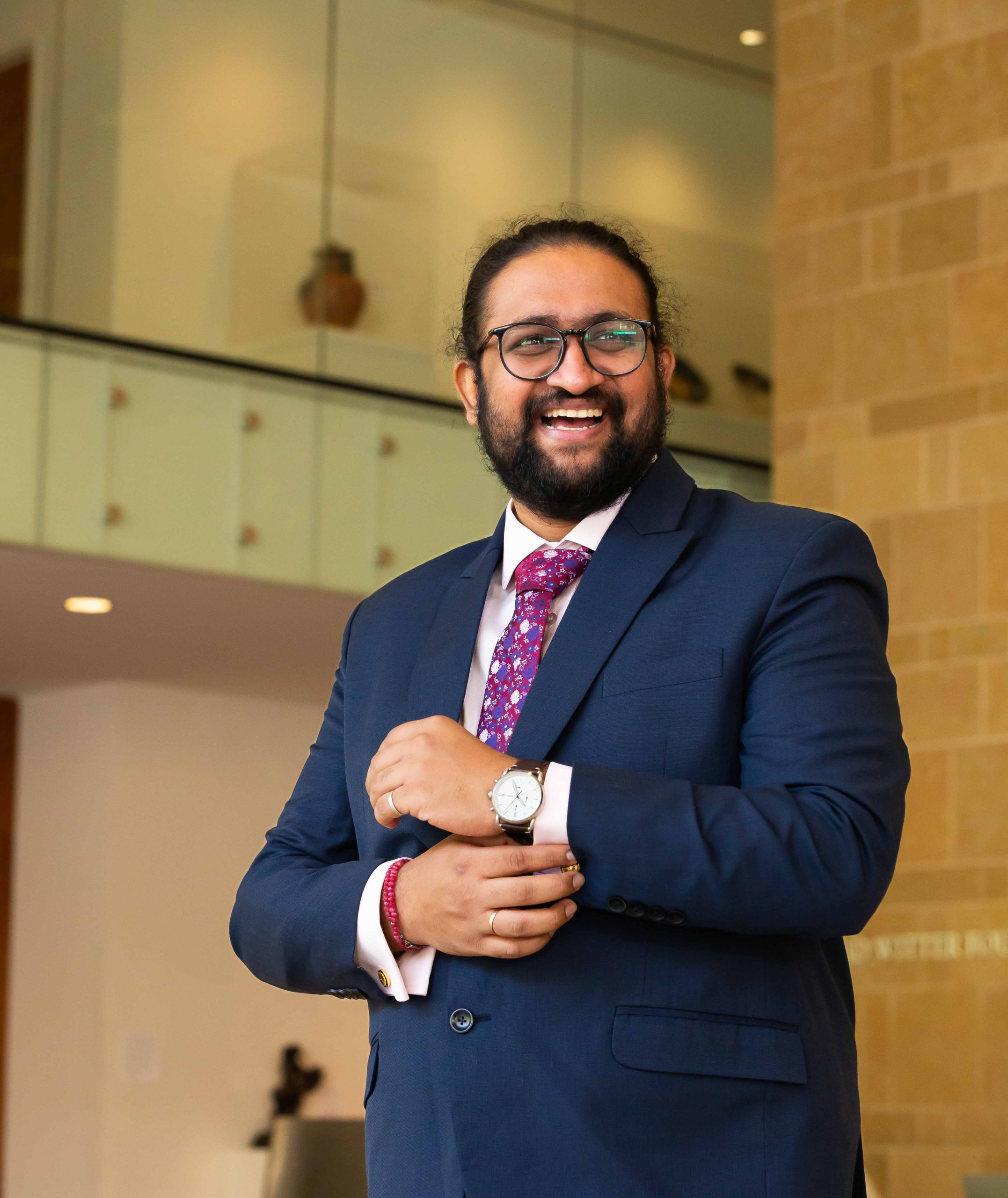 Artist-in-residence, Sri Vamsi Matta, wearing a blue suit with a red tie, in the style of B. R. Ambedkar, the Indian social reformer and political leader. Vamsi is posing in the Chazen Museum of Art in the University of Wisconsin Madison campus.