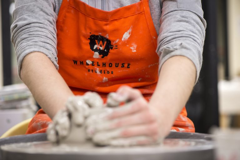 student working with clay on a pottery wheel