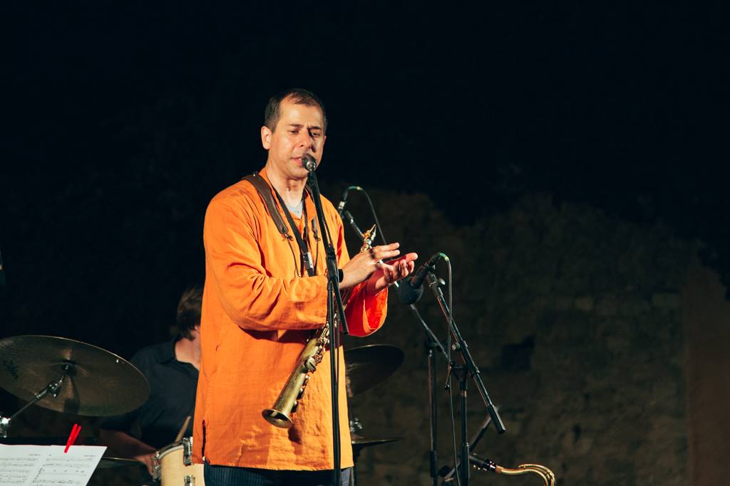 Arun Luthra clapping on stage in front of a microphone stand