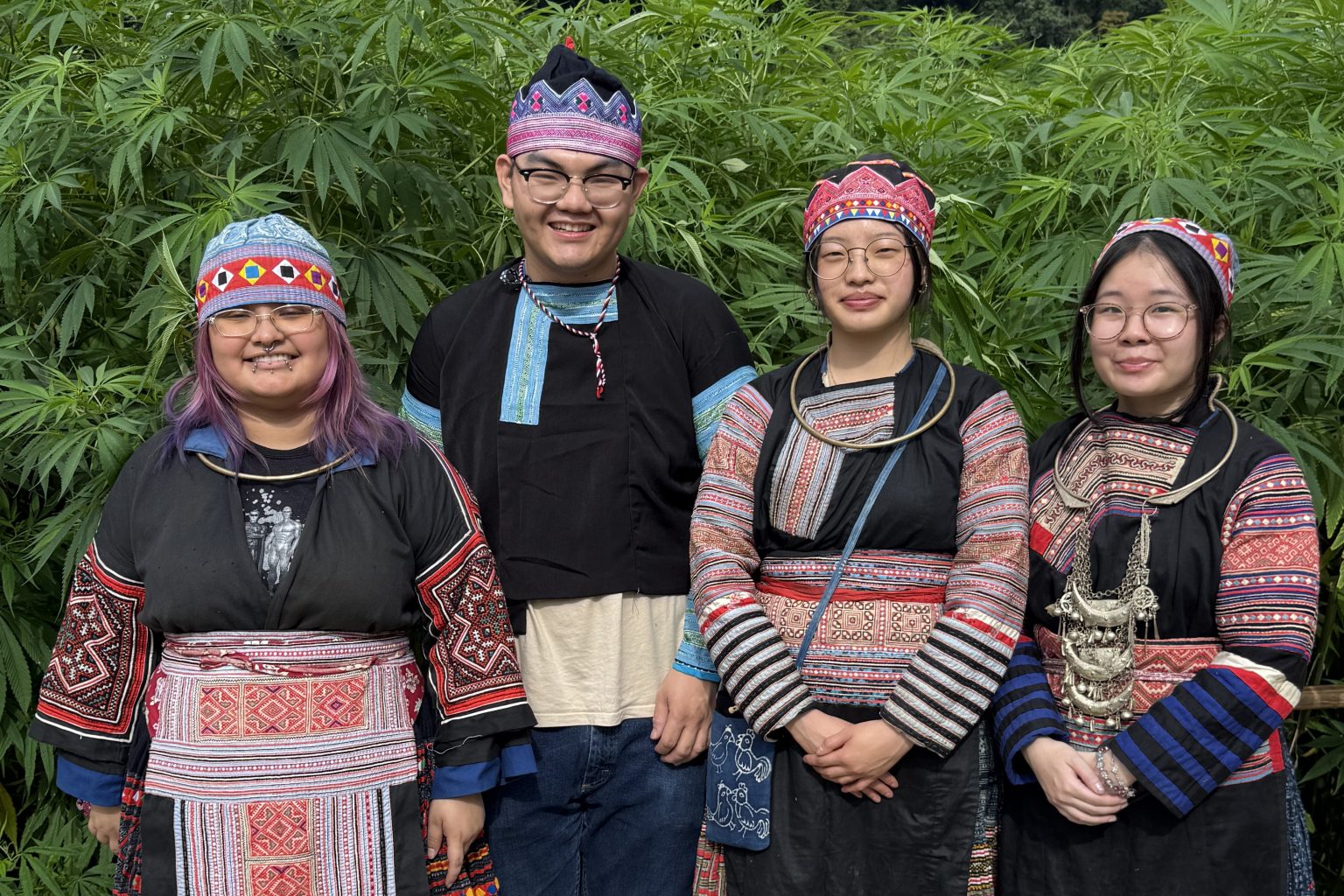 All four students in a row smiling and dressed in traditional Hmong textiles.