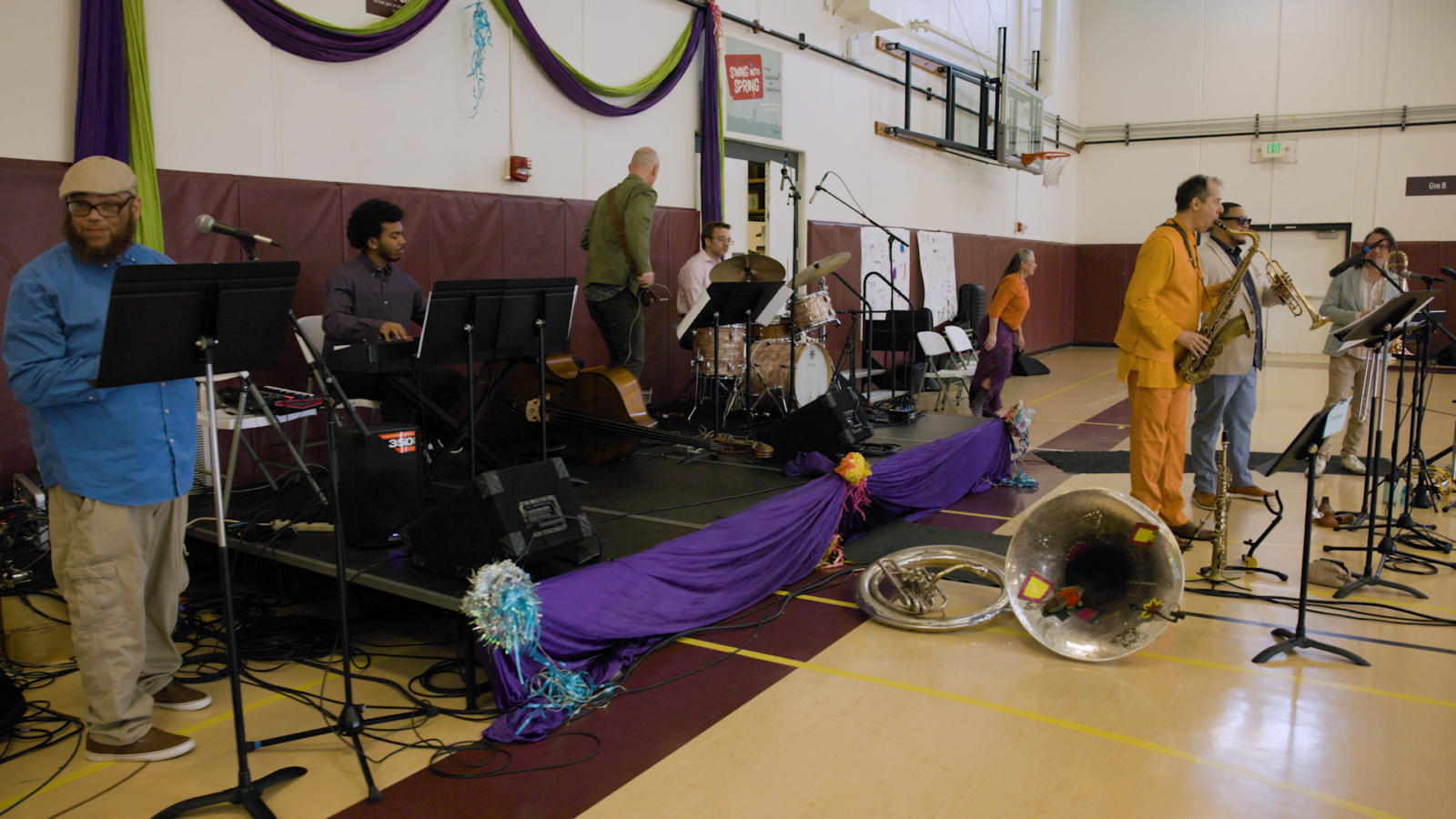 Several members of a jazz band perform in a gymnasium.