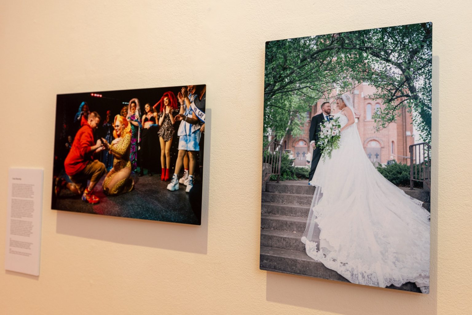 A shot of two photos mounted on the gallery wall. The one on the left shows a proposal and the one on the right is a wedding portrait.