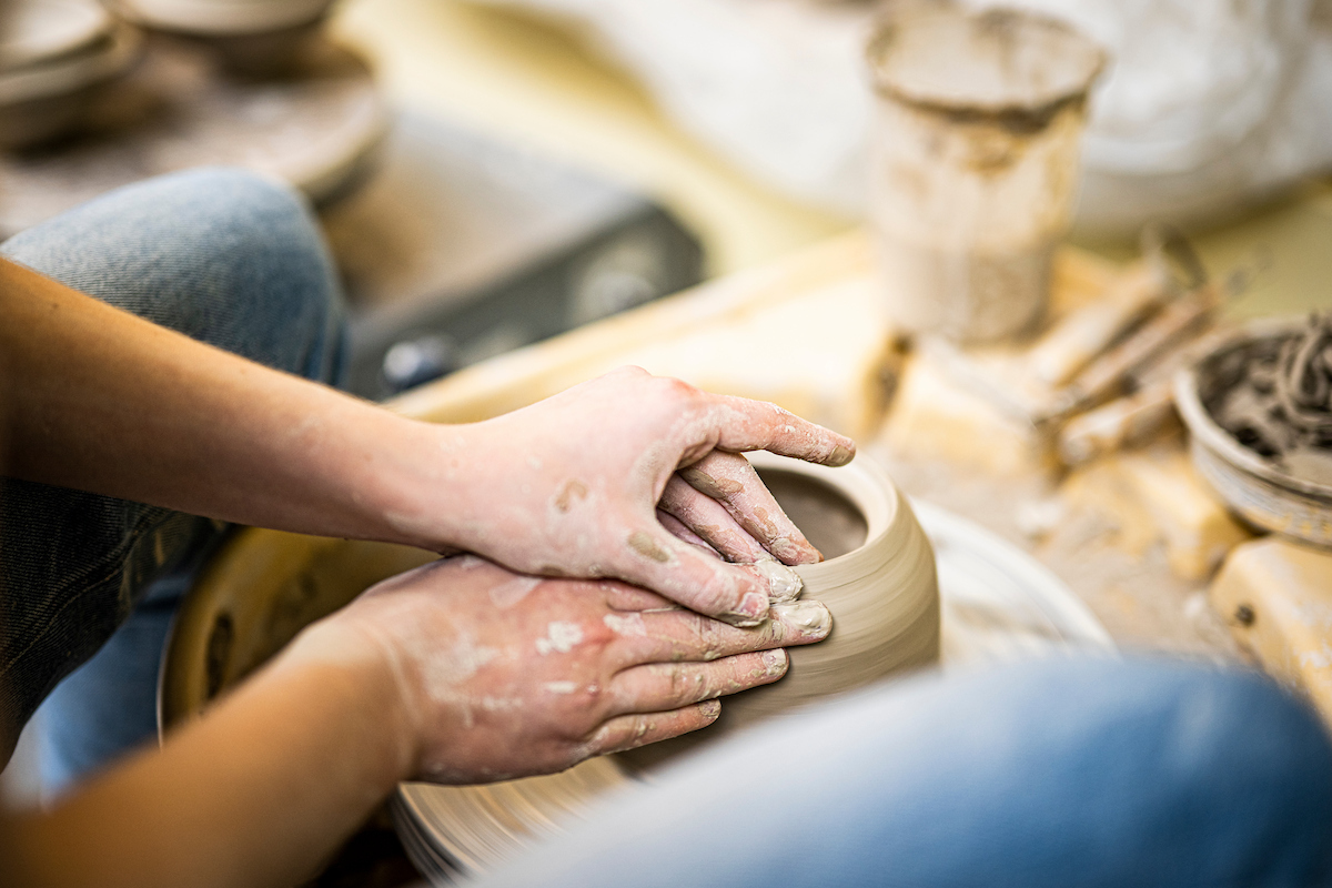 Undergraduate ceramics student Juliana Crooks refines the lip of a wheel-thrown container in the ceramics workshop in the Art Lofts Building at the University of Wisconsin-Madison during an Open Studio Day. (Photo by Bryce Richter / UW–Madison)