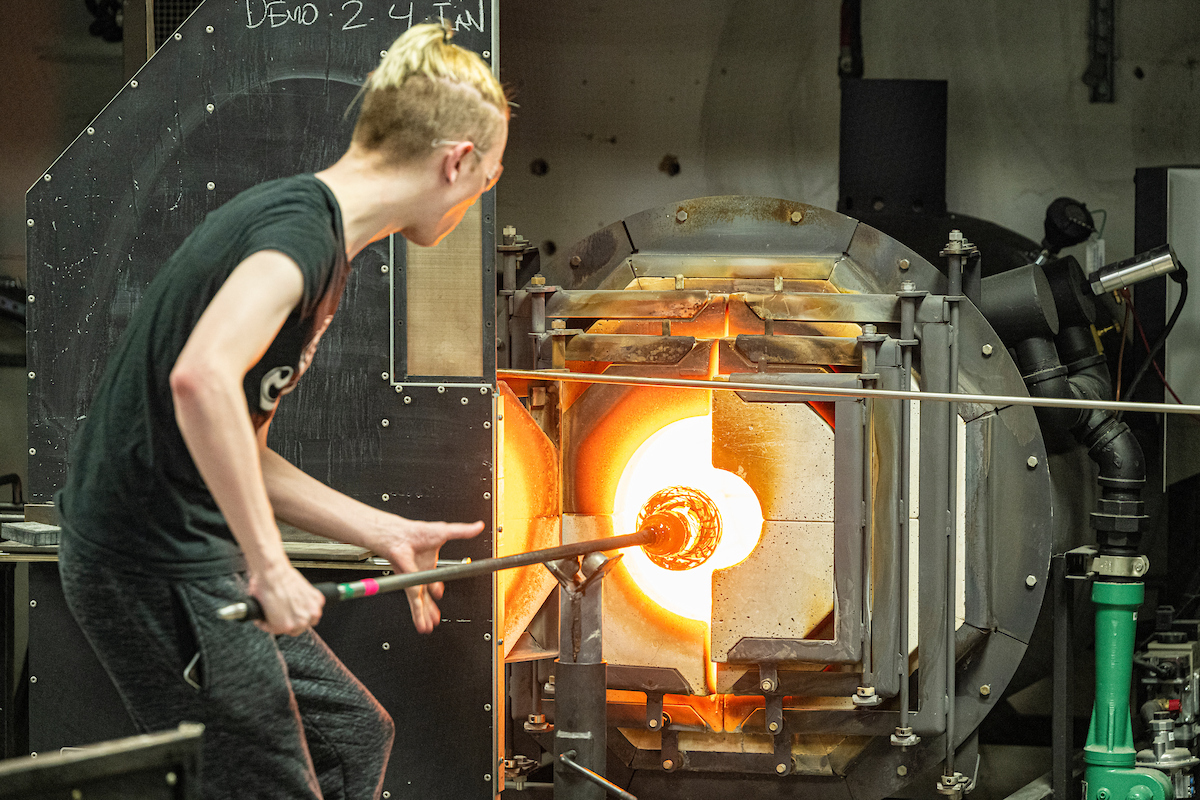 A student assists in a glass blowing demonstration in the Art Department at the University of Wisconsin-Madison. (Photo by Bryce Richter / UW-Madison)