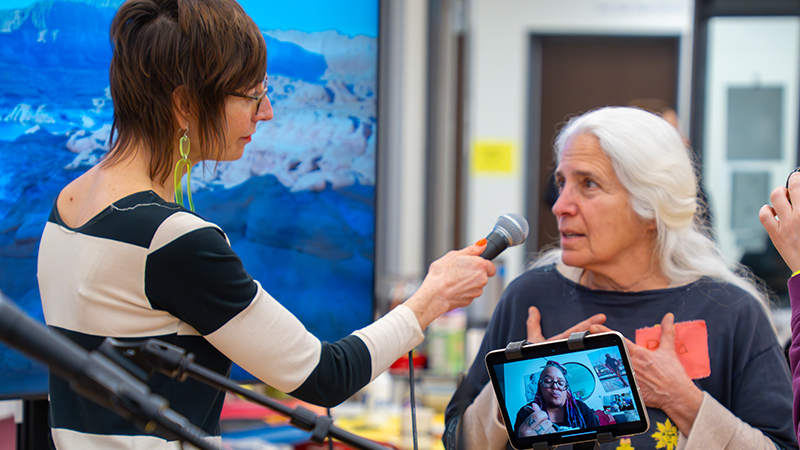 a woman holds a microphone up for another woman to speak